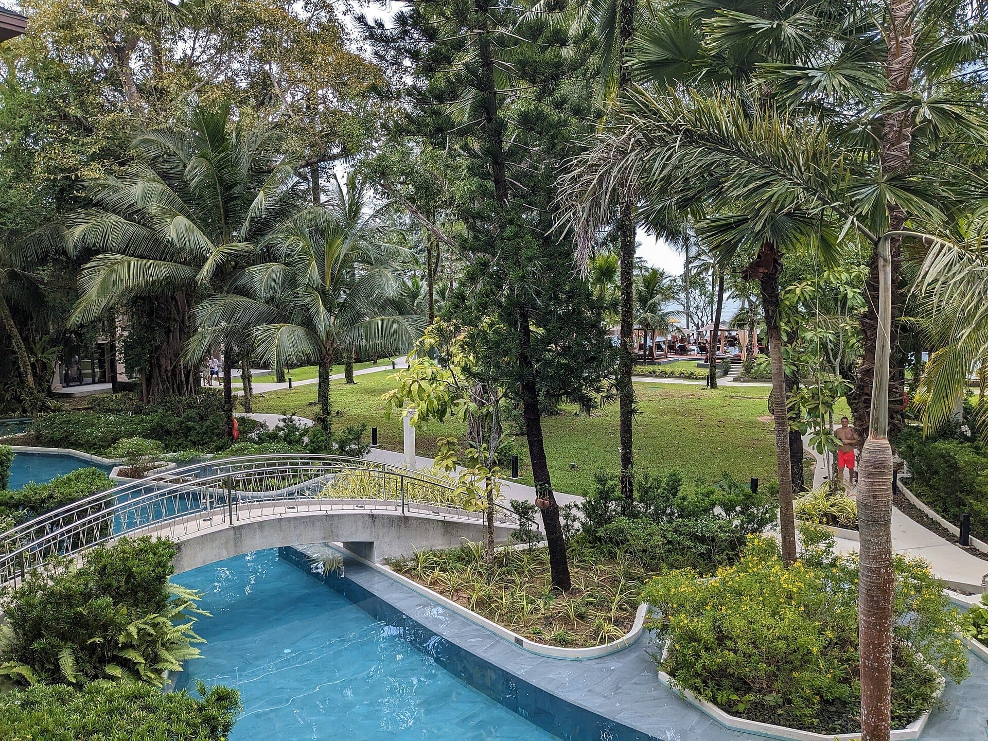The pool at La Flora Khao Lak winding between lawns and palms